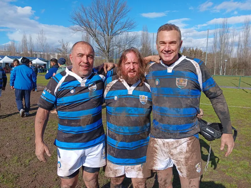 Tres jugadores de Tango Classic's embarrados y sonrientes después de un partido de rugby veterano
