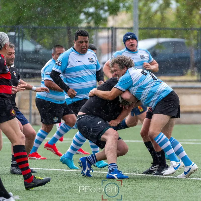 Jugador de Tango Classic's con la camiseta celeste placando a un rival bajo la lluvia (foto: RFotoart)