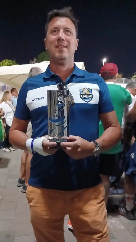 Integrante de Tango Classic's con el polo oficial de Roma Sport sosteniendo un trofeo de un torneo de veteranos